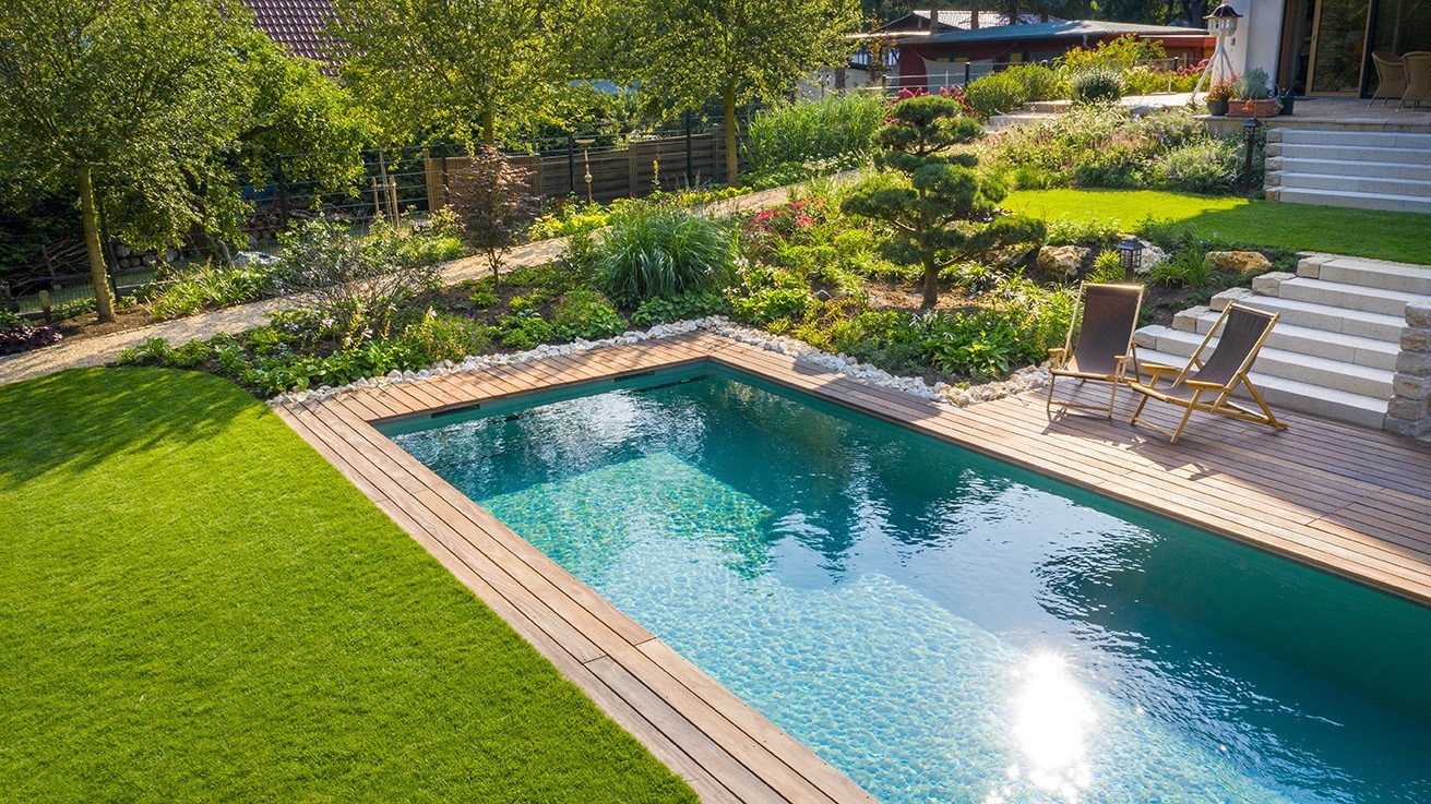 Living Pool von oben mit grünem Rasen, klarem blauen Wasser auf Holzterrasse